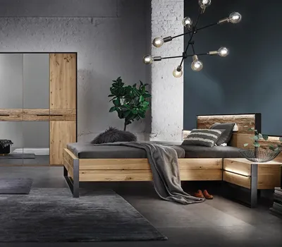Stilvolles Schlafzimmer mit Bett und Kleiderschrank aus Massivholz, schwarzem Metallgestell und moderner Beleuchtung, kombiniert mit eleganter Wandgestaltung im Industrial-Look.